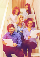 Image showing team with papers and take away coffee on staircase