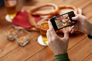 Image showing close up of hands with smartphone picturing beer