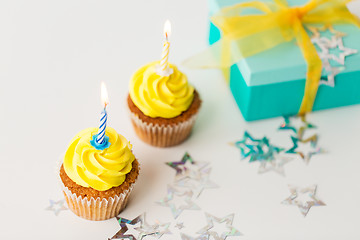 Image showing birthday cupcakes with burning candles and present