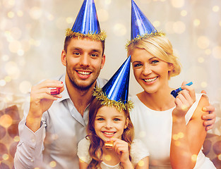 Image showing smiling family in blue hats blowing favor horns