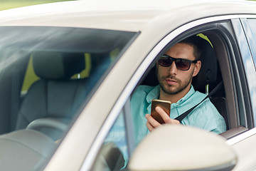 Image showing man in sunglasses driving car with smartphone