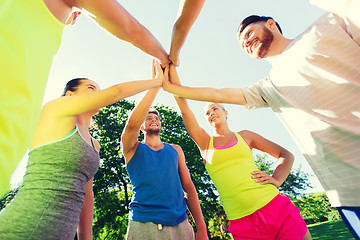 Image showing group of happy friends making high five outdoors