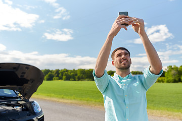 Image showing man with smartphone and broken car at countryside