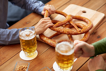 Image showing close up of men drinking beer with pretzels at pub