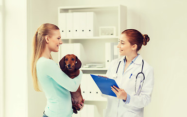 Image showing happy woman with dog and doctor at vet clinic