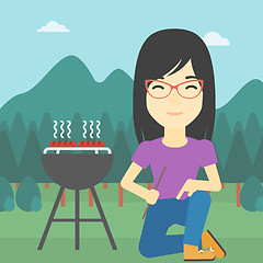 Image showing Woman cooking meat on barbecue.