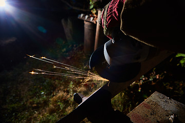 Image showing Worker cutting metal with grinder. Sparks while grinding iron