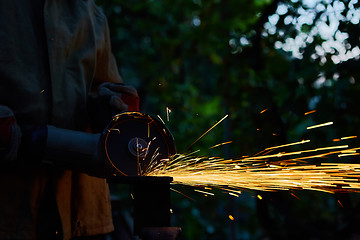 Image showing Worker cutting metal with grinder. Sparks while grinding iron