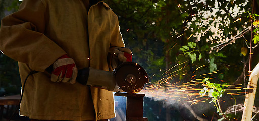 Image showing Worker cutting metal with grinder. Sparks while grinding iron