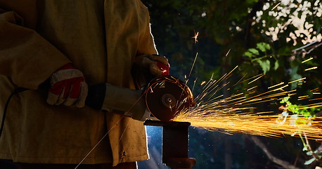 Image showing Worker cutting metal with grinder. Sparks while grinding iron