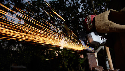 Image showing Worker cutting metal with grinder. Sparks while grinding iron