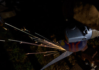 Image showing Worker cutting metal with grinder. Sparks while grinding iron