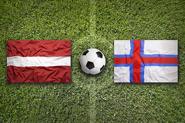 Image showing Latvia and Faroe islands flags on soccer field
