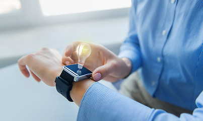 Image showing close up of hands with smart watch and light bulb