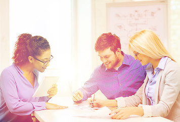 Image showing smiling team with table pc and papers working