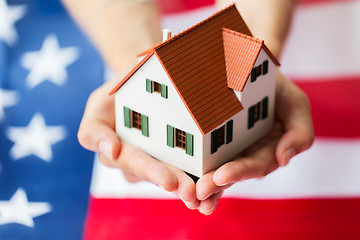 Image showing close up of hands holding house over american flag