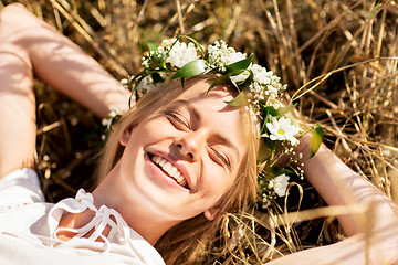 Image showing happy woman in wreath of flowers lying on straw