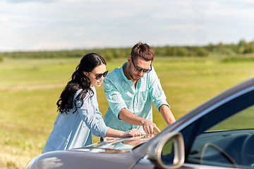 Image showing happy man and woman with road map on car hood