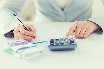 Image showing close up of hands counting money with calculator