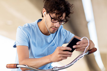 Image showing man with smartphone and earphones on bicycle