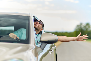 Image showing happy man in shades driving car and waving hand