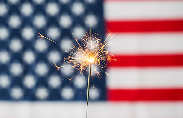Image showing close up of sparkler burning over american flag