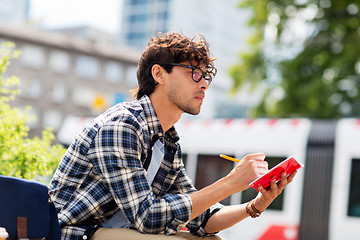 Image showing man with notebook or diary writing on city street