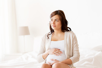 Image showing happy pregnant woman sitting on bed at home