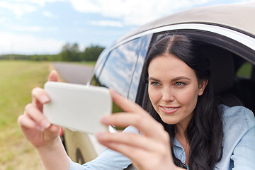 Image showing happy young woman driving in car with smartphone