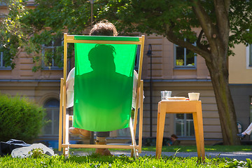 Image showing Silhouette of relaxed man on deckchair in a park