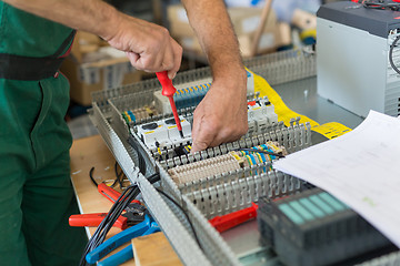 Image showing Electrician assembling industrial electric cabinet.