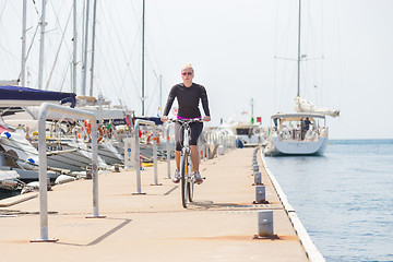 Image showing Young active woman cycling on pier in marina.