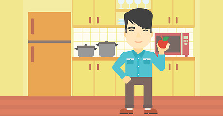 Image showing Young man with apple in the kitchen.