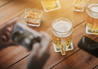 Image showing close up of hands with smartphone picturing beer