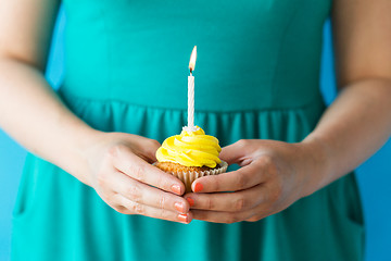 Image showing woman with burning candle on birthday cupcake