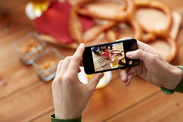 Image showing close up of hands with smartphone picturing beer