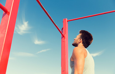 Image showing young man exercising on horizontal bar outdoors