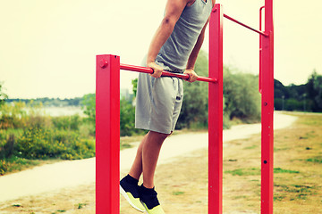 Image showing young man exercising on horizontal bar outdoors