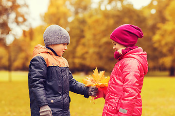 Image showing little boy giving autumn maple leaves to girl