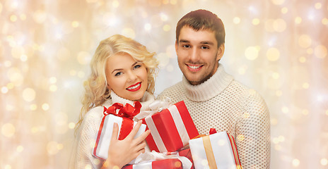 Image showing happy couple in sweaters holding christmas gifts 