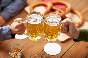 Image showing close up of hands clinking beer mugs at bar or pub