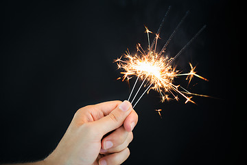 Image showing hand holding sparklers over black background