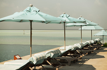 Image showing parasol and sunbeds by sea on maldives beach