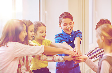 Image showing group of smiling school kids putting hands on top