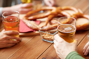 Image showing close up of men drinking beer with pretzels at pub