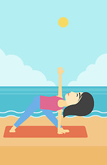 Image showing Woman practicing yoga triangle pose on the beach.