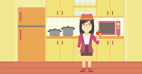 Image showing Young woman with apple in the kitchen.