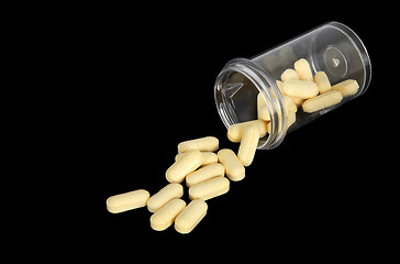 Image showing Yellow pills spilling out of a bottle