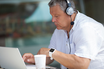 Image showing Elderly man typing on laptop in cafe
