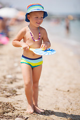 Image showing Lovely smiling bot in hat walking on sandy beach